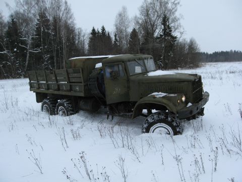 1987 Ford Bronco - A military truck is stuck in a snowy field with trees in the background.