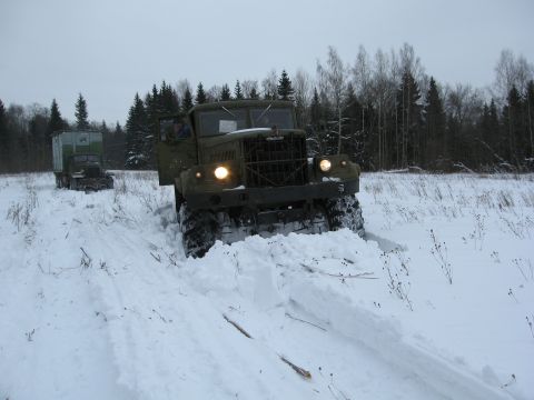 1987 Ford Bronco - Two military trucks navigate a snowy field with trees in the background.