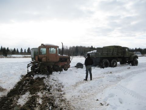1987 Ford Bronco - A person stands between a tractor and a military truck in a snowy landscape.