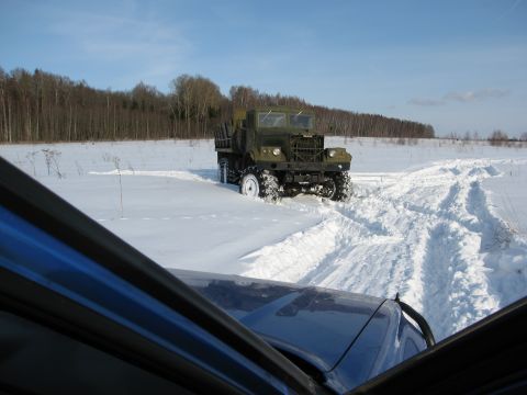 1987 Ford Bronco - A military truck is stuck in a snowy field, with tracks leading away from it.