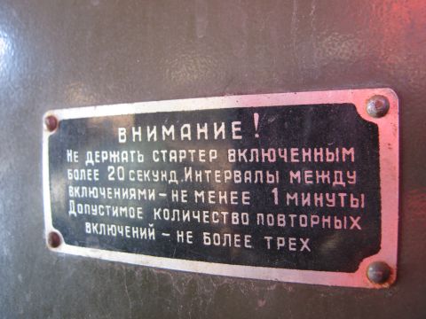 1987 Ford Bronco - A metal plate displays instructions in Russian regarding starter usage limits.