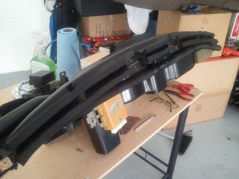 1994 Ford Bronco - A disassembled car dashboard section rests on a workbench, surrounded by tools and cleaning supplies.