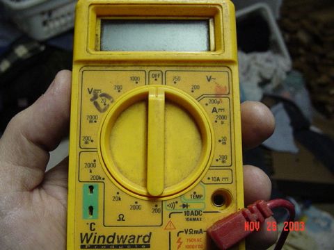1989 Ford Bronco - A yellow multimeter is held in a hand, showing various measurement settings and a digital display. A date stamp is visible in the corner.