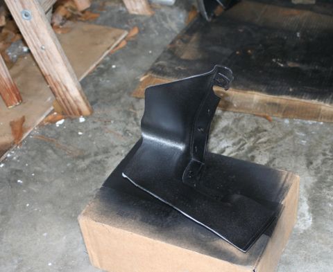 1976 Ford Ranchero - A black car part is being spray painted black, resting on a cardboard box.