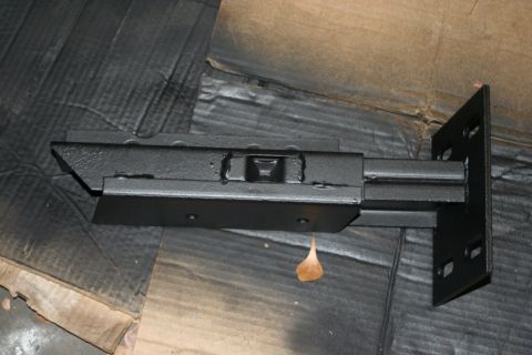 1976 Ford Ranchero - Close-up of a black metal trailer hitch part, likely a receiver or shank, on a cardboard surface.