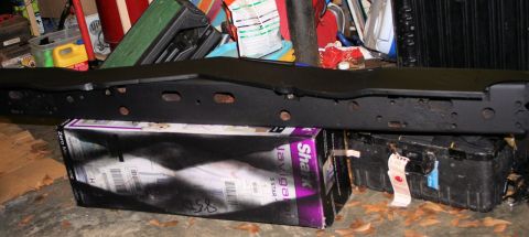 1976 Ford Ranchero - A black bumper part is shown resting on a box in a cluttered garage setting.
