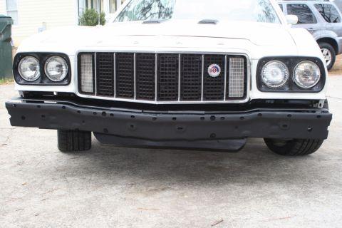 1976 Ford Ranchero - The front of a white 1976 Ford Ranchero is visible, showing its grille and bumper.