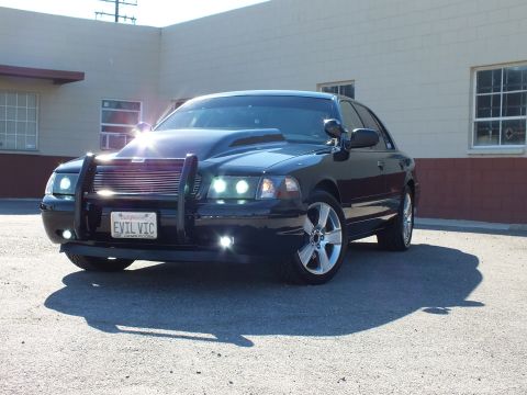 2003 Ford Crown Victoria - A black 2003 Ford Crown Victoria is shown from a three-quarter front view, a custom hood and push bar.