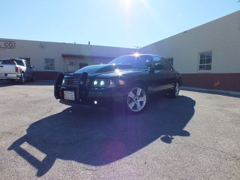 2003 Ford Crown Victoria - Front view of a custom Crown Victoria casting a long shadow, warehouse and parked truck behind it.