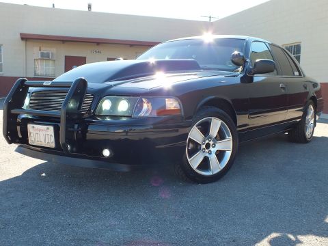 2003 Ford Crown Victoria - Front three-quarter of a custom Crown Victoria, EVIL VIC plate, beside a building marked 12946.