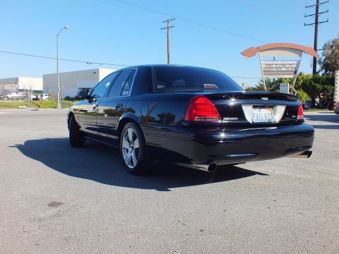 2003 Ford Crown Victoria - Rear-corner view of a custom Crown Victoria with chrome wheels and dual tips under a clear sky.