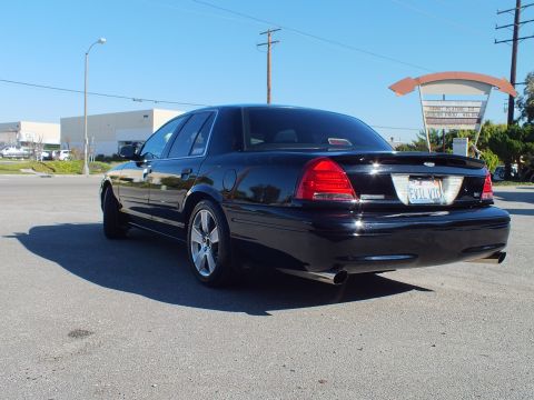 2003 Ford Crown Victoria - Rear three-quarter of a custom Crown Victoria, taillights and chrome wheels, beside utility poles.