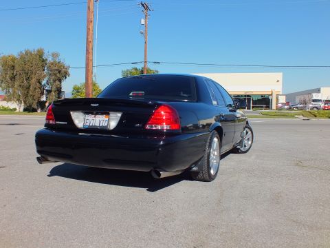 2003 Ford Crown Victoria - Rear-corner view of a custom Crown Victoria, EVIL VIC plate, parked across from a dealership lot.