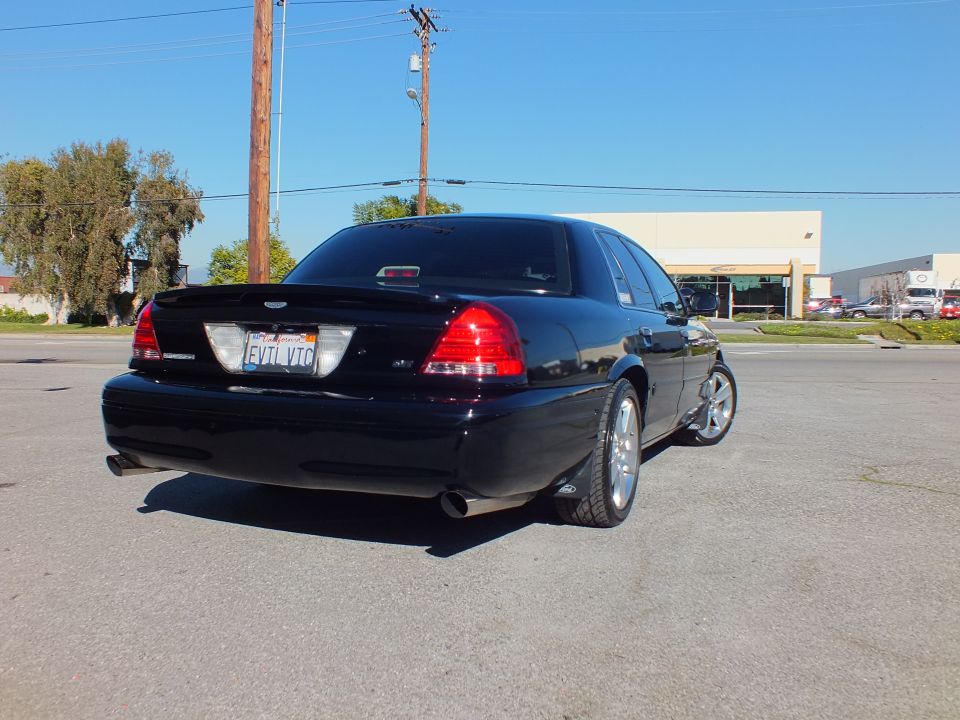 Black Ford Crown Victoria rear three-quarter with dual exhaust and chrome wheels