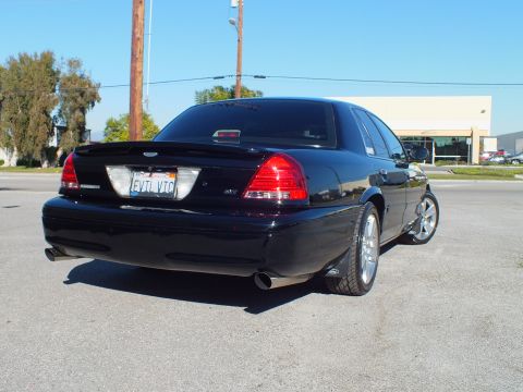 2003 Ford Crown Victoria - Rear-corner shot of a custom Crown Victoria with chrome wheels under utility lines and clear sky.