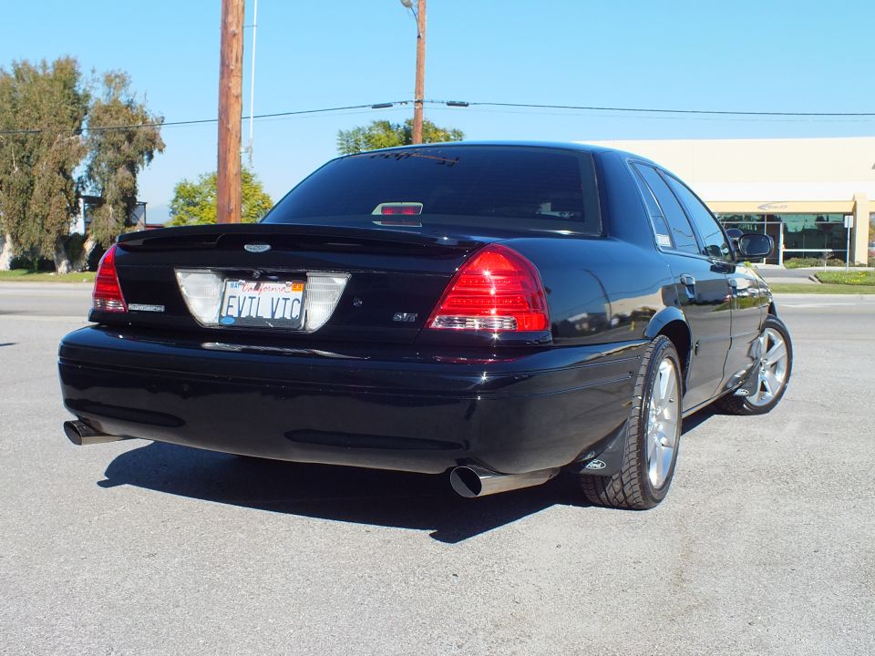 Black Ford Crown Victoria rear three-quarter, taillights lit, dual exhaust, EVIL VIC plate