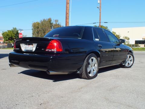 2003 Ford Crown Victoria - Rear-corner view of a custom Crown Victoria with dual exhaust and spoiler beside a stop sign.