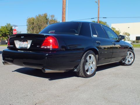 2003 Ford Crown Victoria - Rear three-quarter of a custom Crown Victoria sedan, dual exhaust visible, in an open parking lot.