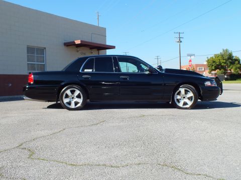 2003 Ford Crown Victoria - Side view of a lowered black sedan with chrome rims and tinted windows in a paved lot