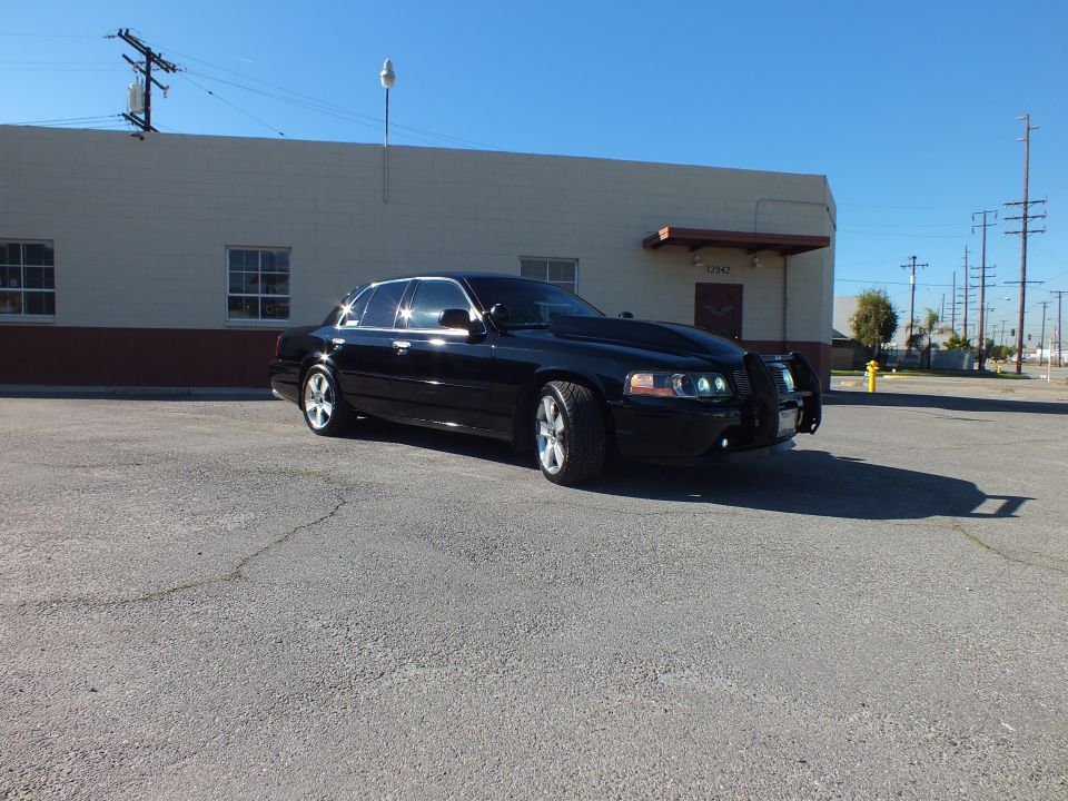 Black Crown Victoria sedan front three-quarter view with grille guard and projector headlights