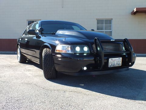 2003 Ford Crown Victoria - Close front view of a black Crown Victoria, billet grille and grille guard, plate reads EVIL VIC