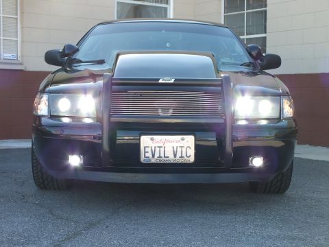 2003 Ford Crown Victoria - Straight-on front of a black sedan with billet grille, scooped hood and EVIL VIC Crown Victoria plate