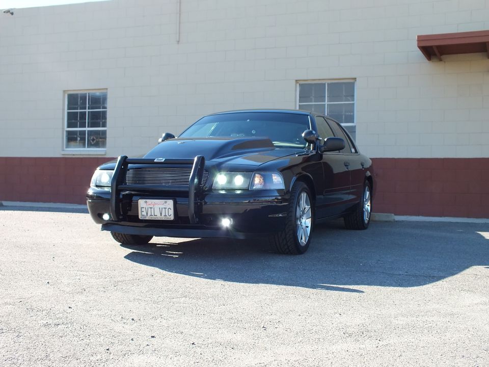 Black Crown Victoria front three-quarter view with grille guard, cowl hood and EVIL VIC plate