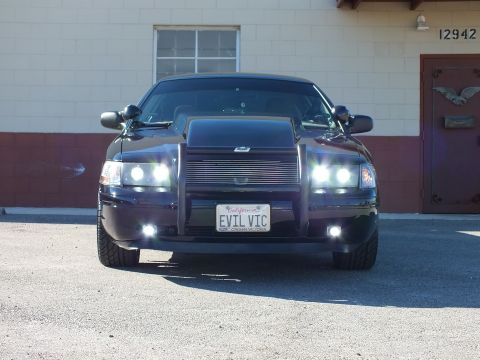 2003 Ford Crown Victoria - Straight-on black sedan, billet grille and grille guard, EVIL VIC plate, parked at building 12942