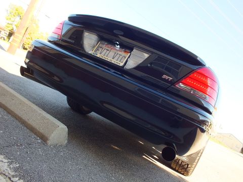 2003 Ford Crown Victoria - Low-angle rear shot of a black sedan showing an SVT badge, EVIL VIC plate and a polished exhaust tip.