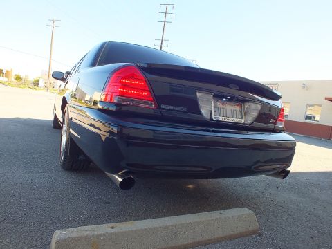 2003 Ford Crown Victoria - Low rear view of a black sedan with LED-style taillights, EVIL VIC plate and a centered exhaust outlet.