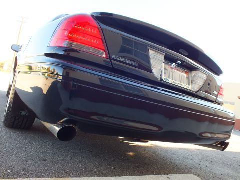 2003 Ford Crown Victoria - Ground-level rear-quarter shot of a black sedan, Police Interceptor lettering, EVIL VIC plate, exhaust tip.