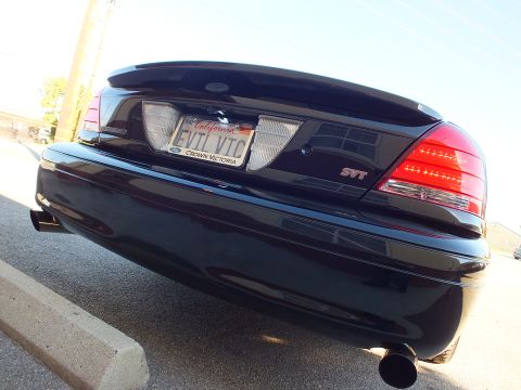2003 Ford Crown Victoria - Black sedan rear from a low angle, SVT badge, EVIL VIC plate and bright red LED taillights.