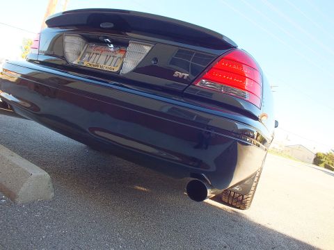 2003 Ford Crown Victoria - Tilted low rear-quarter shot of a black sedan, SVT badge, EVIL VIC plate and a black exhaust outlet.