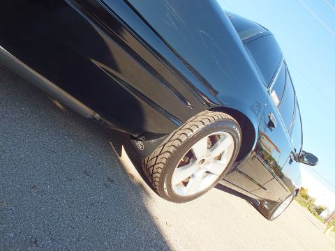 2003 Ford Crown Victoria - Tight low-angle detail of a black sedan rear wheel, polished five-spoke alloy and dropped body line.