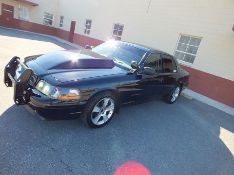 2003 Ford Crown Victoria - Front left view of a black sedan fitted with a tubular brush guard, billet grille and dual projector headlights.
