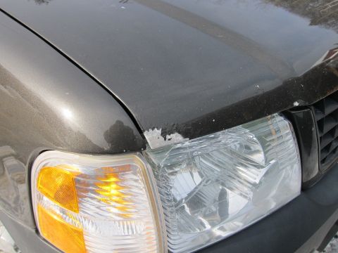 1991 Ford Crown Victoria LTD - Close-up of a car's front corner, showing damage to the paint and headlight assembly.