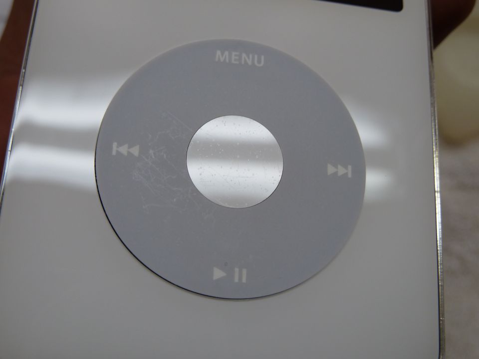 Scratched click wheel and MENU text on a silver iPod Classic