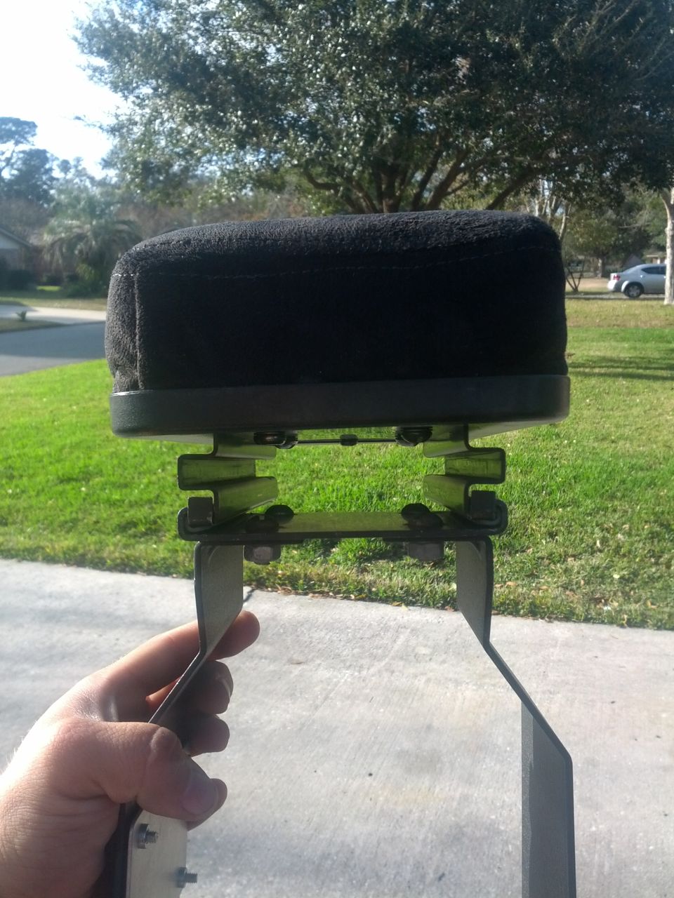 Hand holding a black air filter assembly with metal brackets and green rubber isolators