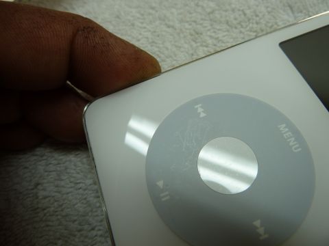 2007 Subaru Impreza - A finger rests on the edge of a white iPod Classic, showing wear on the click wheel.