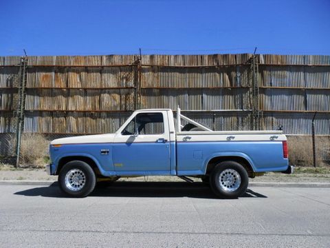 1983 Ford F-100 - Side profile of a two-tone Ford pickup truck with a roll bar in the bed.