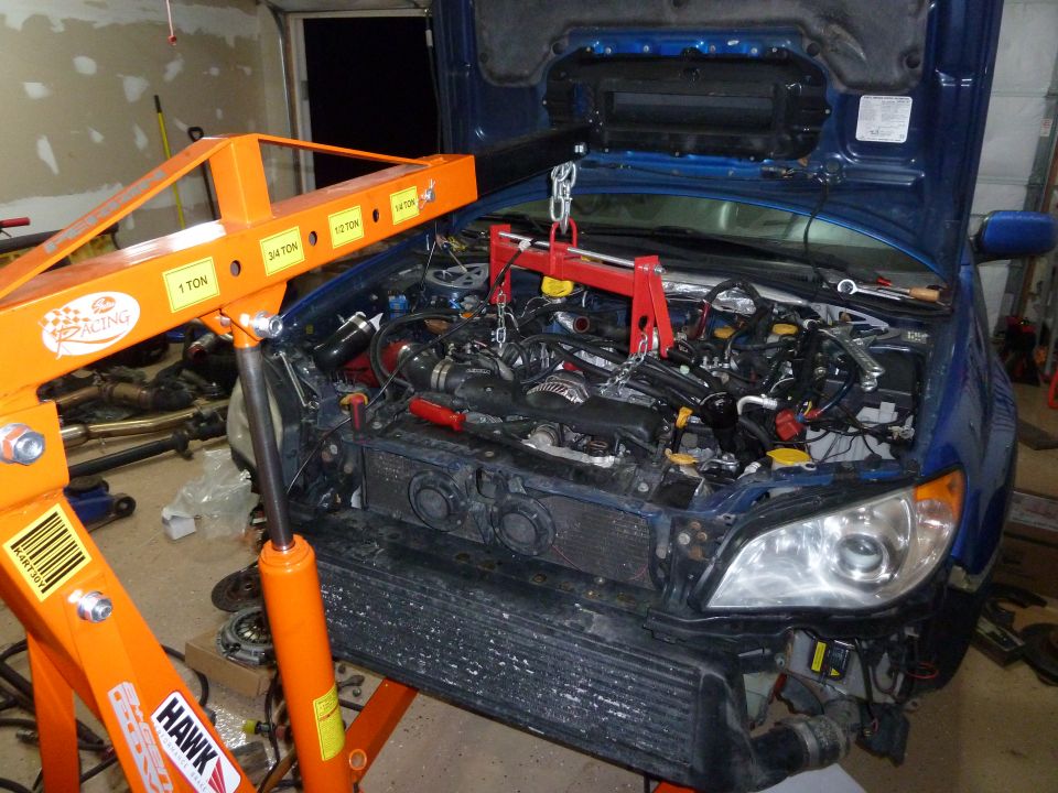 Blue Subaru Impreza engine bay with engine hoist, front bumper removed, engine partially disassembled