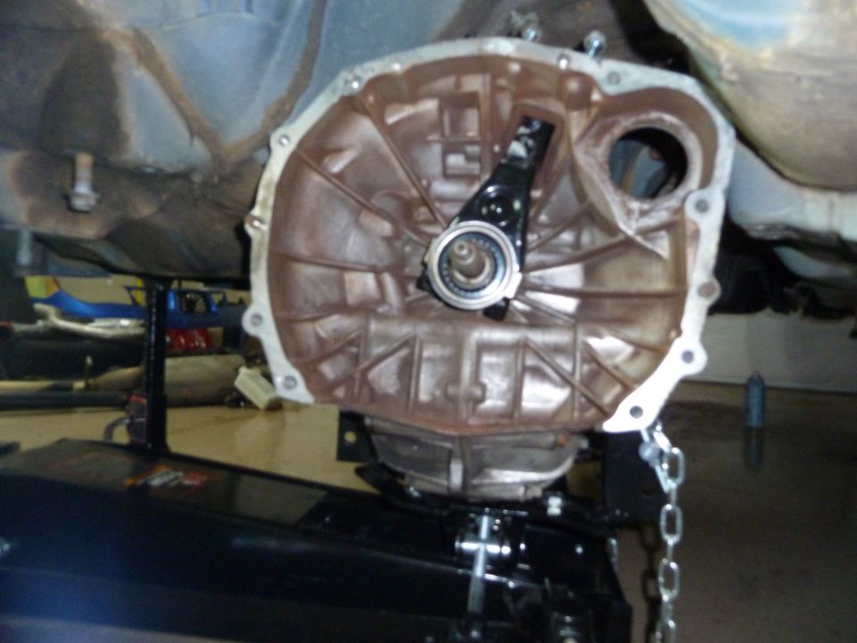Transmission bell housing and clutch fork assembly removed from vehicle, supported by a jack