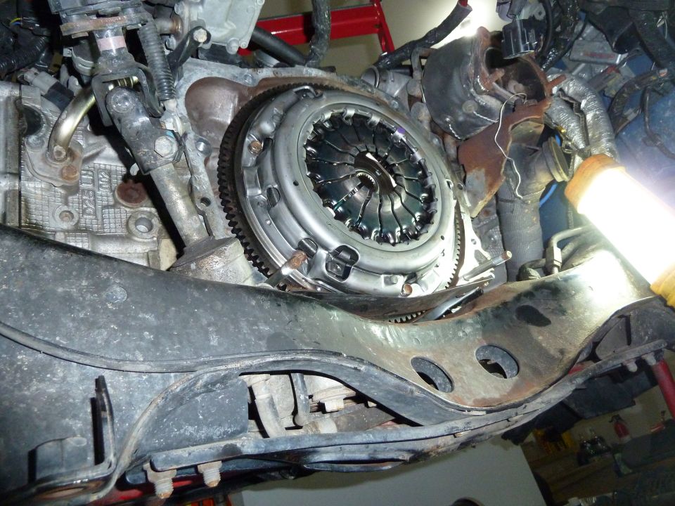 Close-up of a vehicle's clutch assembly and flywheel, with engine components visible