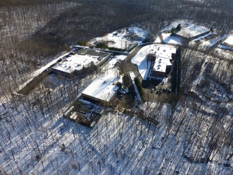 1959 Kenworth W900A - An aerial perspective captures industrial buildings and parking areas within a snow-covered forest landscape.