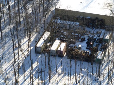 1959 Kenworth W900A - An aerial shot captures a snowy junkyard scene with multiple trailers and scattered vehicle parts.