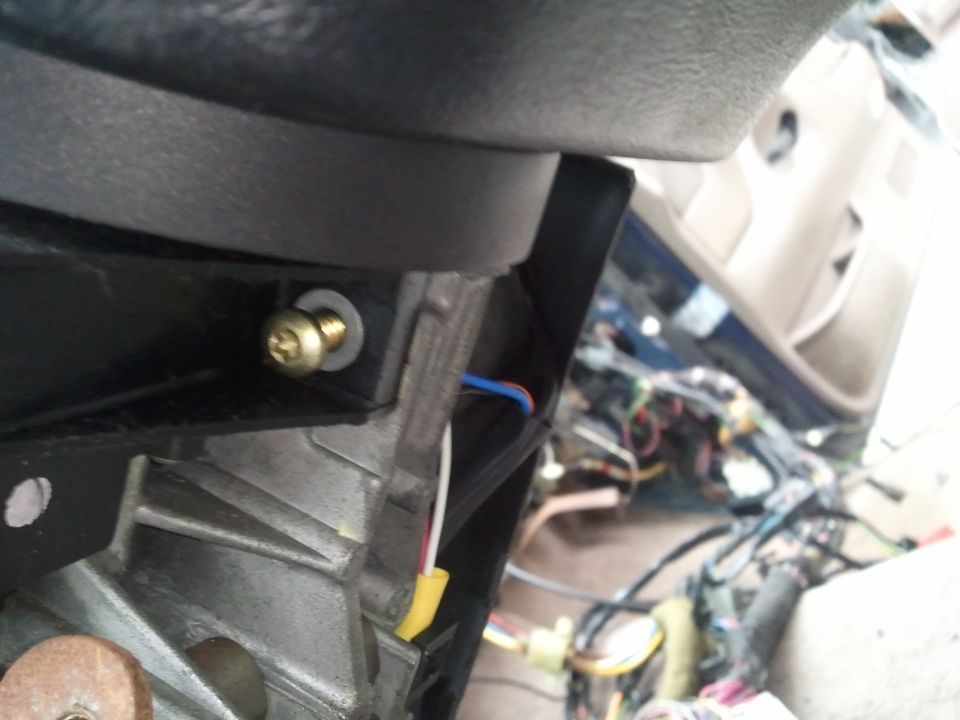 Vehicle interior showing exposed wiring and a screw with a washer