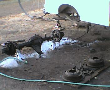 1984 Ford Bronco - Ford 10.25 rear axle assembly being worked on, with brake drums and other parts visible.