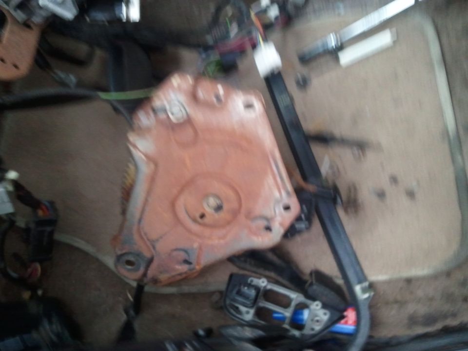 Close-up of a rusty metal seat mounting bracket with wiring visible