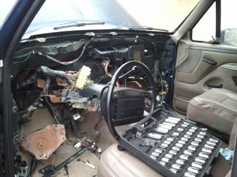 1994 Ford Bronco - The interior of a vehicle shows a disassembled dashboard with exposed wiring and a toolbox on the seat.