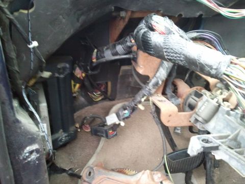 1994 Ford Bronco - Close-up view of the complex wiring harness and components located under the dashboard of a vehicle.
